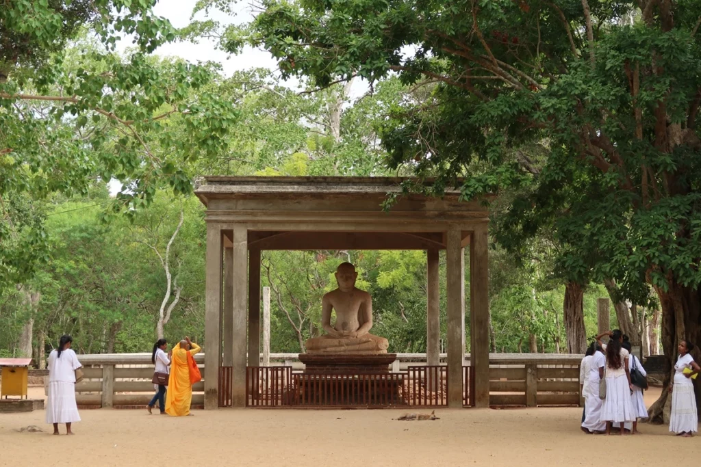 Moniale devant une statue de Bouddha au Sri Lanka